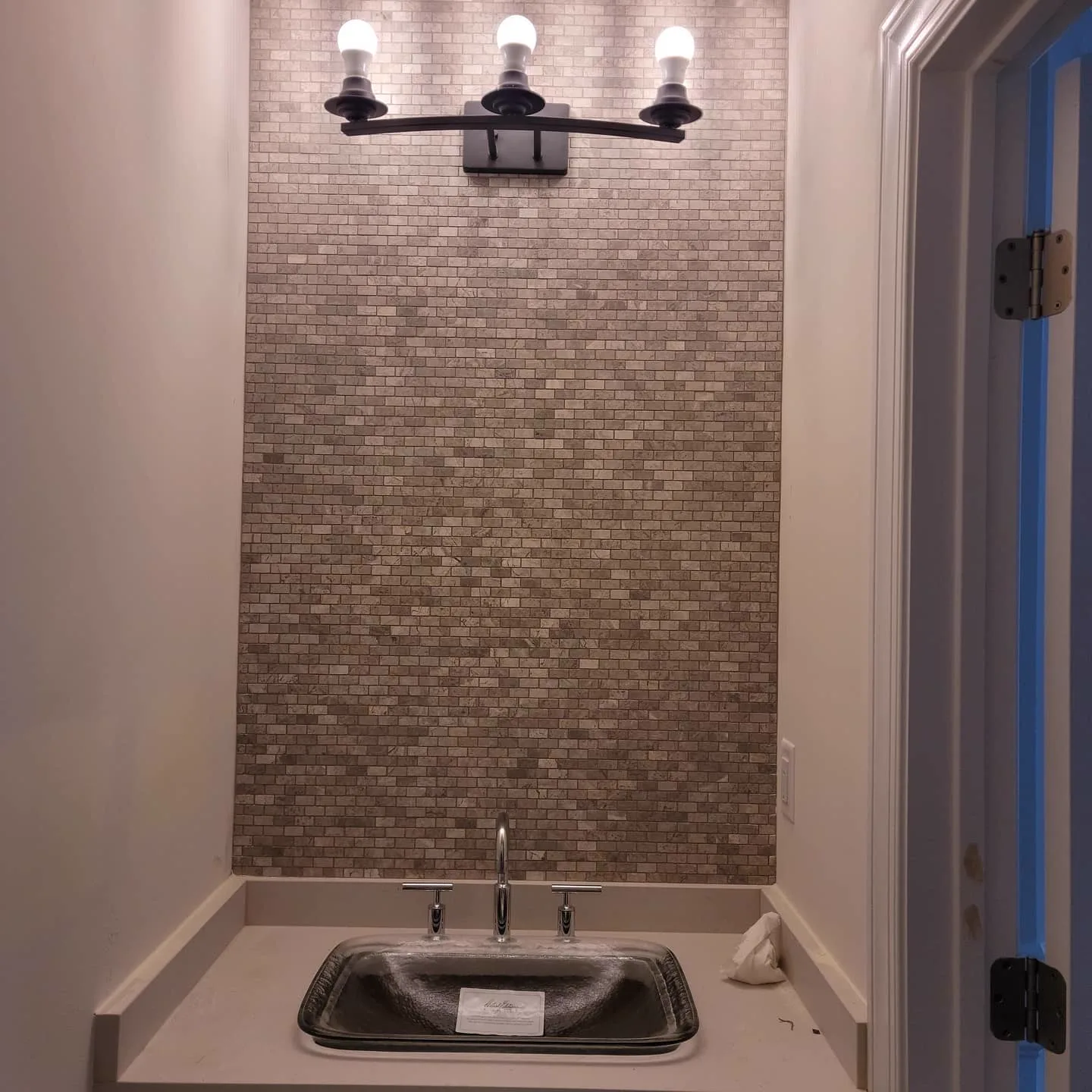 Mosaic accent wall behind a bathroom pedestal sink